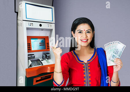 Eine Frau mit Geld zeigen nach Rücktritt vom Geldautomaten Stockfoto