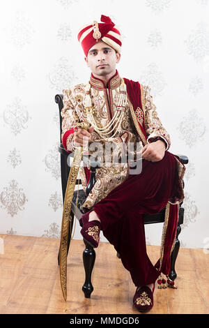 Ful-Length 1 Royal Rajasthani Bräutigam Stuhl Ehe Sherwani mit Schwert Stockfoto