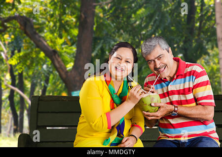 Gerne alte Paar Bank teilen Trinken Kokosnussmilch genießen In-Garden Stockfoto