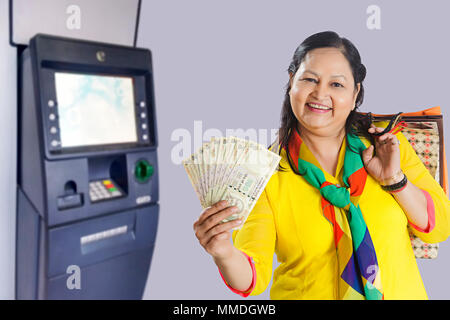 Alte Frau mit Geld Rupien Banknoten mit shopping-bags - am Geldautomaten Stockfoto