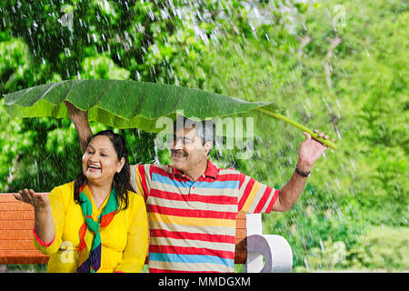 Gerne alte Paar Sitzen unter Banana-Leaves Spaß At-Park Stockfoto