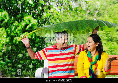 Gerne älteres Paar Bank unter Banana-Leaves Regen. Sicherheit Garten Stockfoto