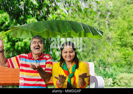 Gerne alte Paar Bank Park unter Banana-Leaves Regen. Genießen Stockfoto