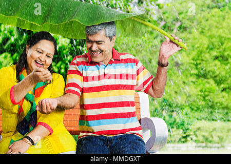 Gerne älteres Paar unter Banana-Leaf strömenden Regen. Hände Spaß Garten Stockfoto