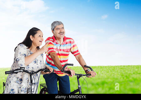 Senior Married-Couple sitzen Zyklus und Frau zeigt auf etwas In-Park Stockfoto