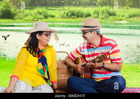 Senior Paar dating Spaß mit Gitarre auf Picknick Near-Lake Stockfoto