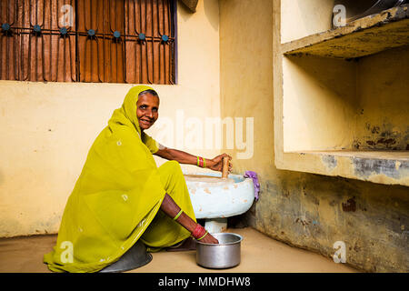 Eine ländliche alten weiblichen Mahlen Weizen mit hand Mühle Vor-ort-Dorf Stockfoto