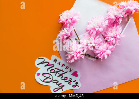 Blumen Grußkarte Konzept, flach. Muttertag. Ausschreibung Frühjahr Bild. Rosa Umschlag voll von verschiedenen Blumen. Flach. Liebe Konzept. Grußkarte auf orange Hintergrund. rosa Blüten Stockfoto