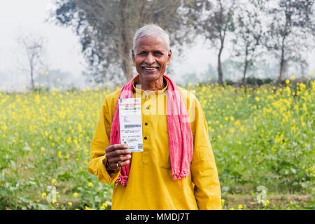 Ein älterer Mann Villager anzeigen Aadhaar-Card Regierung-Id In-Farm ländlichen Dorf Stockfoto