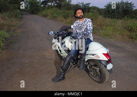 Junger Mann in weißer Kleidung mit einem weißen leistungsstarke Motorrad Stockfoto