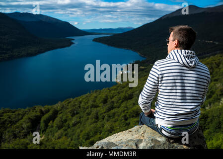 Kerl sitzt auf der Kante einer Klippe. Stockfoto