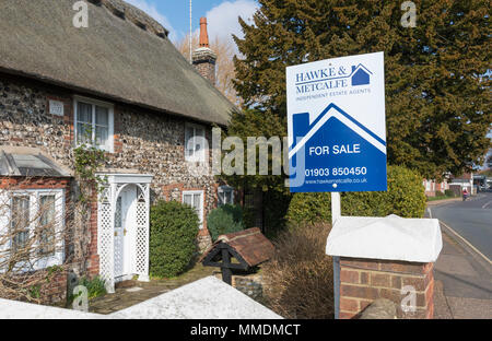 Für Verkauf Zeichen von Hawke & Metcalfe Immobilienmakler ein Haus für Verkauf in einem Dorf in England, Großbritannien. Stockfoto