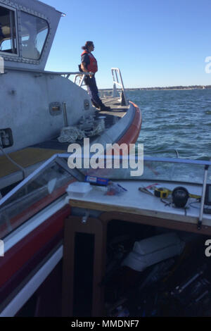 Die Küstenwache unterstützt drei Personen nach ihrem Schiff ab Nehmen auf Wasser in der Nähe von Pine Island, Connecticut, Freitag, Oktober 20, 2018. Ein Coast Guard Station New London 45-Fuß-Antwort Boat-Medium (RB-M) die Besatzung auf die Szene kam, begann die Entwässerung des Schiffes, dann mit dem Boot nach Groton Öffentliche Bootsrampe in Groton, Anschl. (US-abgeschleppt Coast Guard Foto von Petty Officer 2. Klasse Peter Beaulieu) Stockfoto