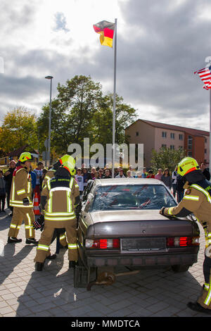 Feuerwehrmänner an die US Army Garrison Ansbach zugeordnet ist, um ein Nutzfahrzeug zu stabilisieren und eine hydraulische Spreuverteiler-Cutter und andere Rettungsgeräte in den Ausbau des Daches und "rescue" Dr. Marshall Blankenship die Direktion der lokalen High School zu unterstützen, als Person, im Auto während der Brandschutz Woche Übung an der High School Ansbach, Ansbach, Deutschland, Okt. 11, 2017 gefangen. (U.S. Armee Fotos von visuellen Informationen Spezialist Eugen Warkentin) Stockfoto