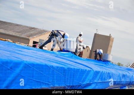 Mitglieder der 156 Tiefbau squadron Reparatur des Dachs durch Hurrikan Maria an der Muniz Air National Base, Puerto Rico beschädigt mit einer der weithin anerkannten FEMA blaue Blätter. (U.S. Air National Guard Foto vom Kapitän Matt Murphy) Stockfoto