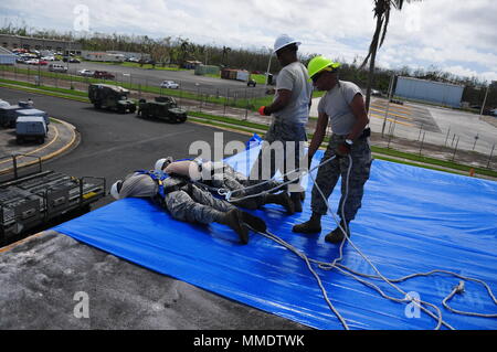 Mitglieder der 156 Tiefbau squadron Reparatur des Dachs durch Hurrikan Maria an der Muniz Air National Base, Puerto Rico beschädigt mit einer der weithin anerkannten FEMA blaue Blätter. (U.S. Air National Guard Foto vom Kapitän Matt Murphy) Stockfoto