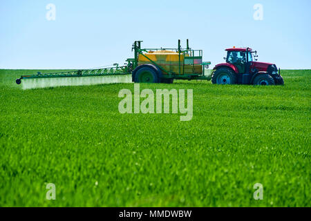 Traktor Weizenfeld mit Spritze Spritzen Stockfoto