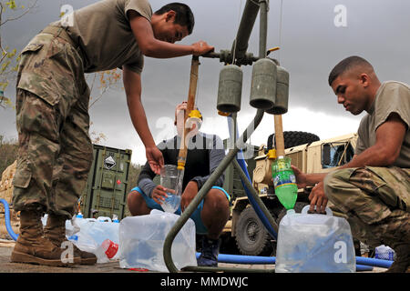 Pfc. Javier Ortiz, Links, ein mit der 127 Quartiermeister und SPC. Andrea Bertarello, ein Generator Mechaniker mit Unterstützung der 659th Maintenance Company, beide aus Fort Bragg, North Carolina, füllen Sie Behälter mit gereinigtem Wasser aus Lagos Dos Bocas in Utuado, Puerto Rico, Okt. 23, 2017. Ortiz, der aus Kalifornien und Bertarello, die aus Italien, werden helfen, die lokale Bewohner aus den Gemeinden Utuado und Arecibo mit Trinkwasser. Die Soldaten sind unter Wasser aus dem See und reinigt es durch einen 1.500 GPH taktische Reinstwassersystem Stockfoto