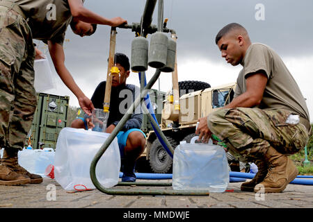 Pfc. Javier Ortiz, Links, ein mit der 127 Quartiermeister und SPC. Andrea Bertarello, ein Generator Mechaniker mit Unterstützung der 659th Maintenance Company, beide aus Fort Bragg, North Carolina, füllen Sie Behälter mit gereinigtem Wasser aus Lagos Dos Bocas in Utuado, Puerto Rico, Okt. 23, 2017. Ortiz, der aus Kalifornien und Bertarello, die aus Italien, werden helfen, die lokale Bewohner aus den Gemeinden Utuado und Arecibo mit Trinkwasser. Die Soldaten sind unter Wasser aus dem See und reinigt es durch einen 1.500 GPH taktische Reinstwassersystem Stockfoto