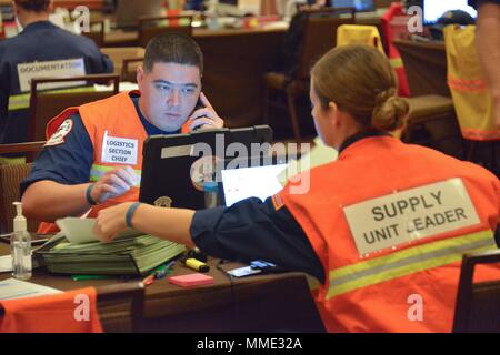 U.S. Coast Guard Chief Warrant Officer Stephen Bishop, die Logistik Section Chief, und Petty Officer 2nd class Cassidy Stevens, der Supply Unit Leader, um die Ressourcen an der Hurrikan Maria ESF-10 PR Unified Command Incident Command Post in San Juan, Puerto Rico, Okt. 20, 2017. Die Maria ESF-10 PR Unified Command, bestehend aus der Abteilung der natürlichen und ökologischen Ressourcen, der U.S. Coast Guard in Verbindung mit dem Puerto Rico Environmental Quality Control Board, Umweltschutz und der USA und Fish & Wildlife Service, reagiert auf Schiffe beschädigt werden, Stockfoto