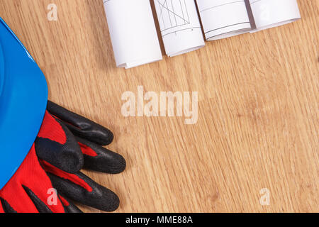 Rollen von Diagrammen und elektrische Konstruktionszeichnungen, blauen Helm und Handschuhe, Zubehör für Ingenieur/in, kopieren Sie Raum für Text an Bord Stockfoto