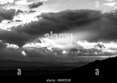 Sonnenuntergang über einem Tal, mit Sonnenstrahlen, die sich durch einige Wolken Stockfoto