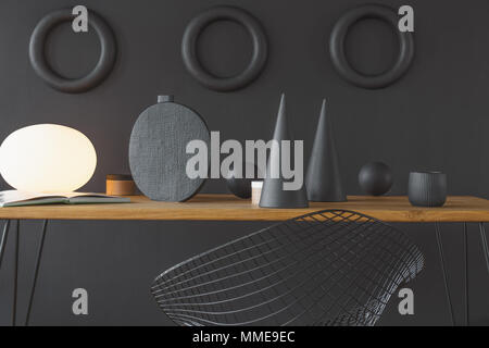 Geometrische Dekorationen auf die schwarze Wand und Holztisch im Home Office Interior Stockfoto