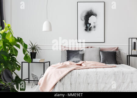 Grau und Silber Kissen liegen auf einem Bett mit weißer Bettwäsche und rosa Decke in femininen Schlafzimmer Innenraum Stockfoto