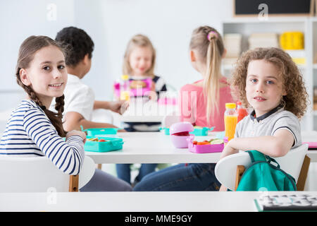 Lächelnde Mädchen und junge, gesunde Frühstück während der Pausen in der Schule Stockfoto