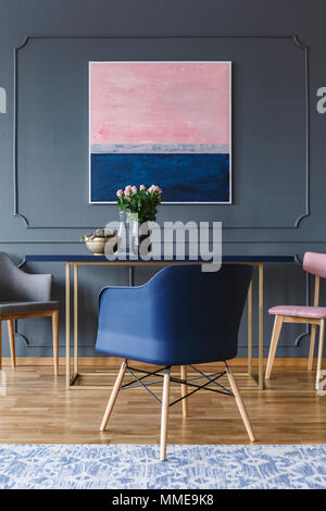 Marine Blau Sessel in der Nähe der Tisch mit Blumen in grau Wohnung Interieur mit rosa Malerei Stockfoto