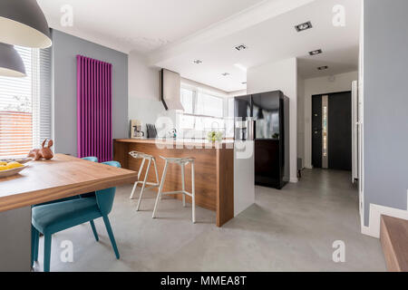 Esszimmer, Küche und Eingang in moderne Familie Haus mit minimalistischen grau Design, farbige Akzente und Holzmöbeln ausgestattet. Stockfoto