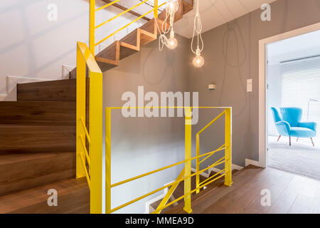 Holztreppe mit gelben Geländer in moderner, stilvoller Eingangsbereich mit Vintage lampe Pendelleuchte und weiße Wand Stockfoto