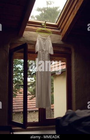 Hochzeit Kleid hängen an der Wand gegen ein Fenster im Dim romantisches Licht in der Landschaft Stockfoto