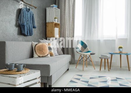 Moderne minimalistische Wohnzimmer Interieur in den Farben Cyan mit Sofa mit Kissen, Sessel, Couchtisch, Schlempe aus Holz und Fenster wit Stockfoto