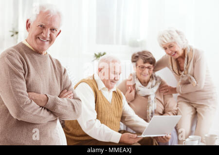 Gerne älterer Mann und seine Freunde mit Laptop Stockfoto