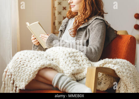 Glückliche junge Frau mit einem Buch in einem Stuhl Stockfoto