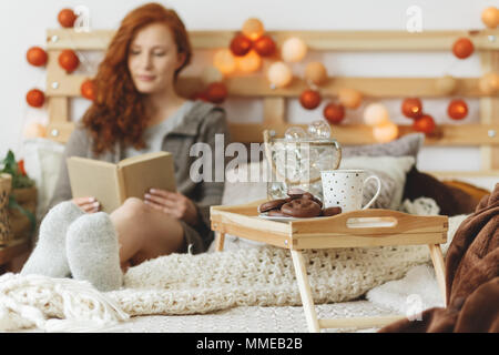 Junge Frau entspannen und ein Buch lesen im Bett Stockfoto
