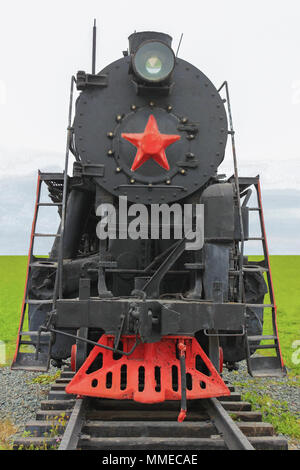 Old soviet locomotive, front view, on the background of green meadows Stockfoto