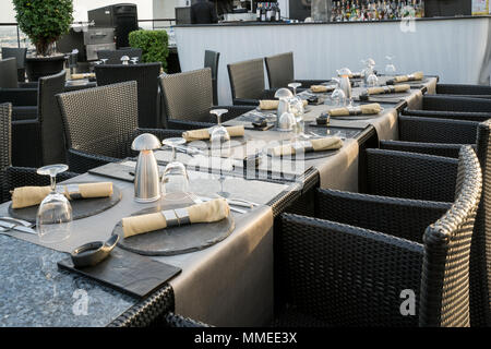 Schuss ein Restaurant Tisch mit leeren Gläser und einen Teller mit einer Serviette auf die Oberseite in Bar auf der Dachterrasse, Restaurant. Stockfoto