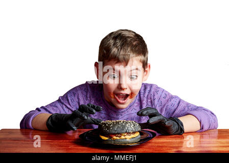 Ein Junge mit einem schwarzen Burger in schwarz Handschuhe Stockfoto