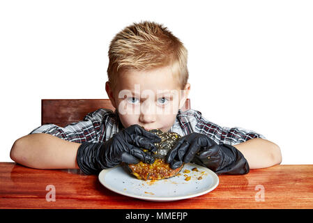 Ein Junge mit schwarzen Handschuhe frisst einen schwarzen Burger Stockfoto