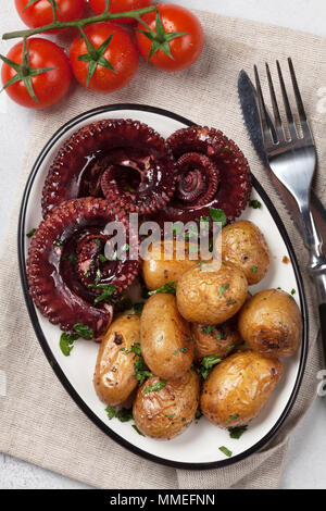 Gegrillter Tintenfisch mit kleinen Kartoffeln mit Kräutern und Gewürzen. Ansicht von oben Stockfoto