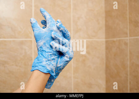 Ein Mädchen wäscht ihre Hände in die Gummihandschuhe Stockfoto