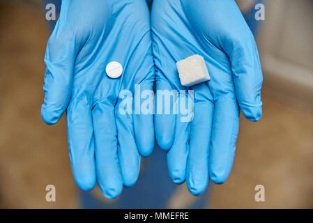 Hände in Handschuhe halten Sie Zucker und einem Tablet Stockfoto