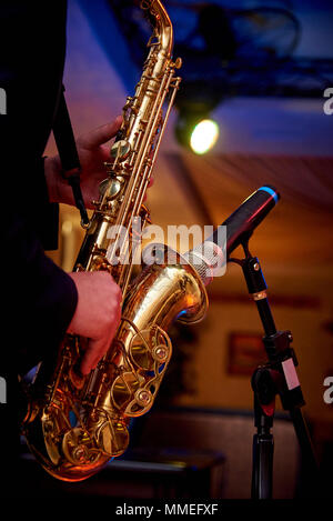 Ein goldenes Saxophon in die Hände eines Musikers in der Nähe des Mikrofons auf dem Zähler Stockfoto