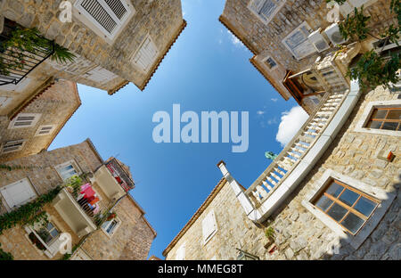 Malerische kleine Piazza mit alten Häusern aus Stein in der Altstadt von Budva, großem Betrachtungswinkel und von unten mit blauem Himmel nach oben, Montenegro Balkan Europa Stockfoto