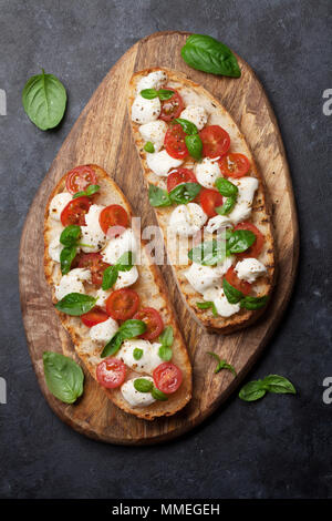 Caprese bruschetta Toasts mit Cocktailtomaten, Mozzarella und Basilikum. Ansicht von oben Stockfoto