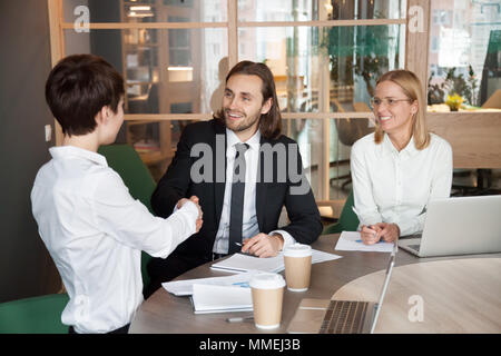 Lächelnd Geschäftsmann und Geschäftsfrau Hände schütteln bei Group mee Stockfoto