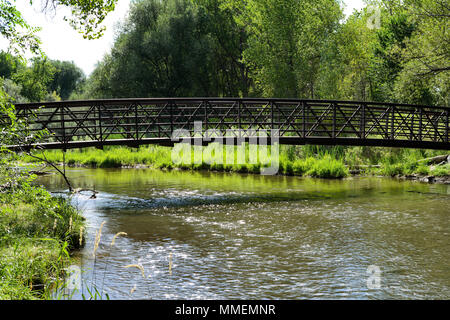 Sommer Creek - ein Bügeleisen trail Brücke über einen kompletten Sommer Creek. Bear Creek, Denver-Lakewood, Colorado, USA. Stockfoto