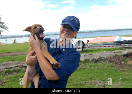 Petty Officer 1st Class Jana James spielt mit ihrem Neu Hund gerettet, Soldat, auf dem Rasen von San Juan, Puerto Rico, Okt. 28, 2018. James, ein reservist mit Marine Safety Unit Savannah, GA., bereitgestellt von San Juan für 60 Tage zur Unterstützung der Hurrikan Maria Antwort. U.S. Coast Guard Foto von Petty Officer 2. Klasse Matthew Masaschi. Stockfoto